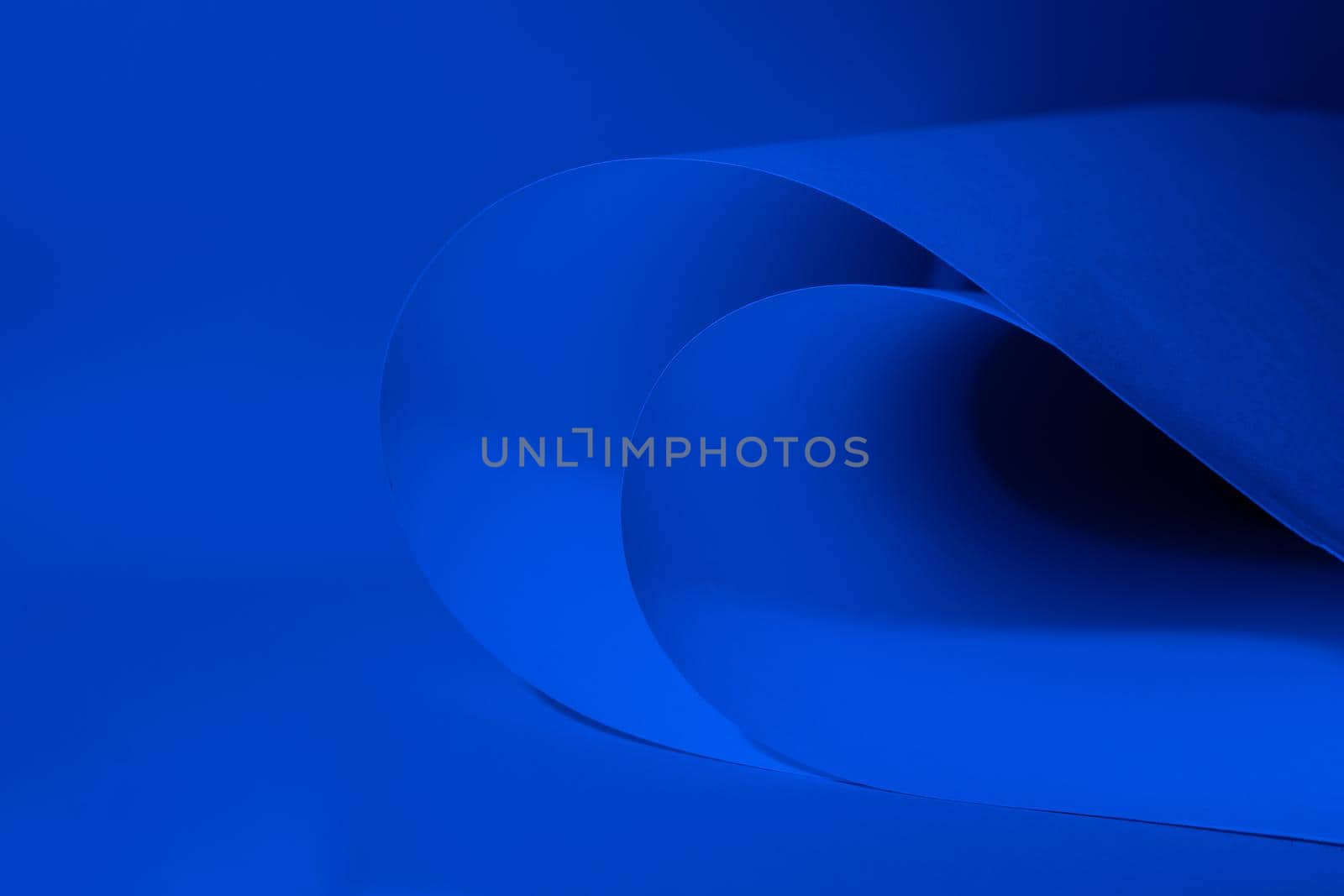Abstract colored background, created with curved blue paper sheets. Curved lines and shapes and soft vivid colors.