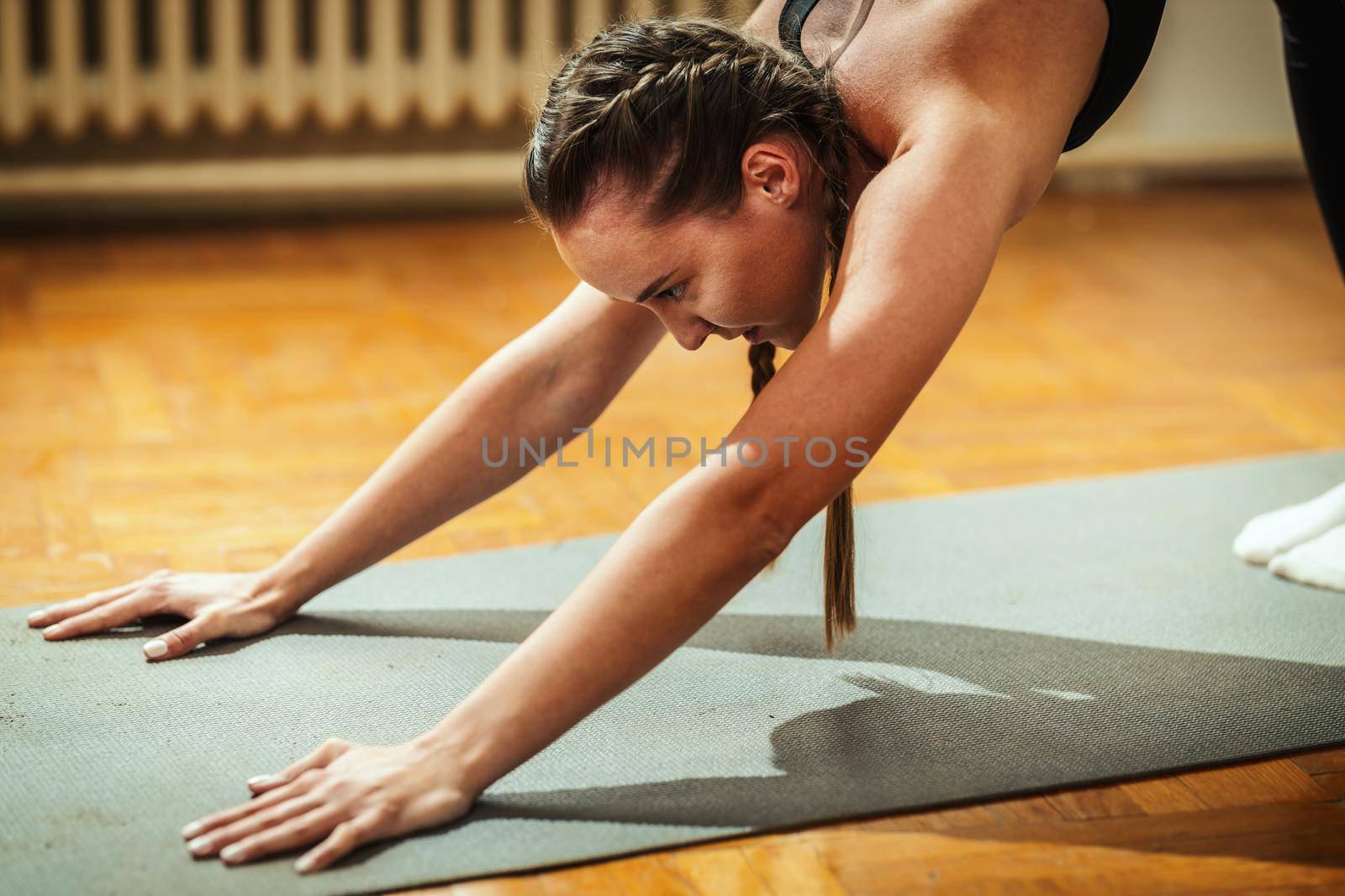 Close-up of a beautiful fit young woman is doing yoga pose and stretching at the apartment .