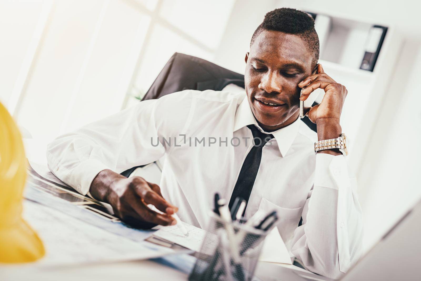 Successful African businessman talking on smartphone in modern office. 