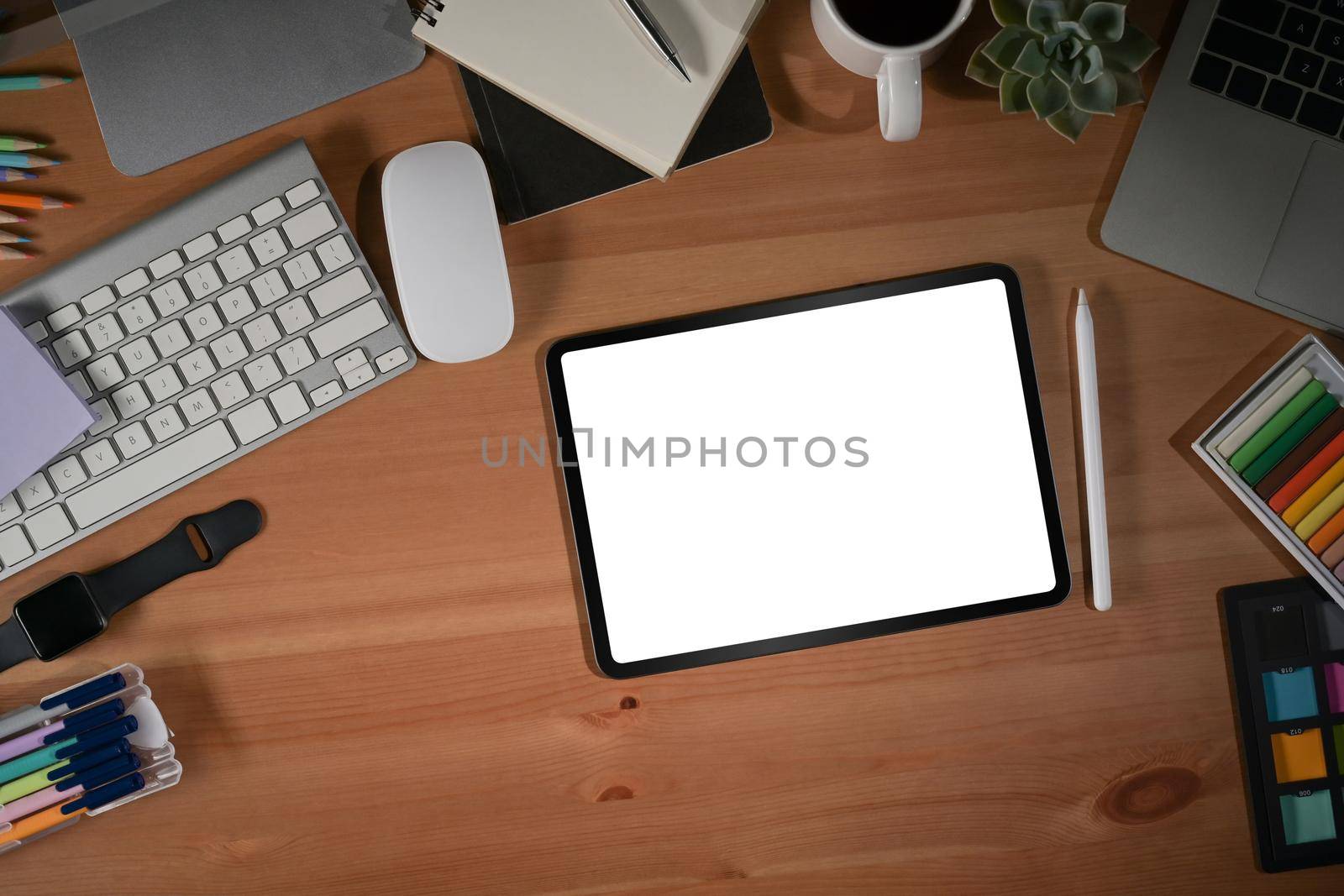 Graphic designer workplace with digital tablet, computer and stationery on wooden table.