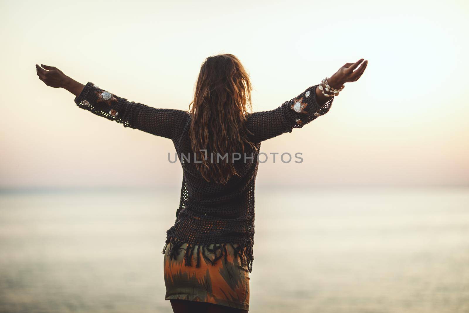 A beautiful young woman is having fun and relaxing on the beach at the sunset. 