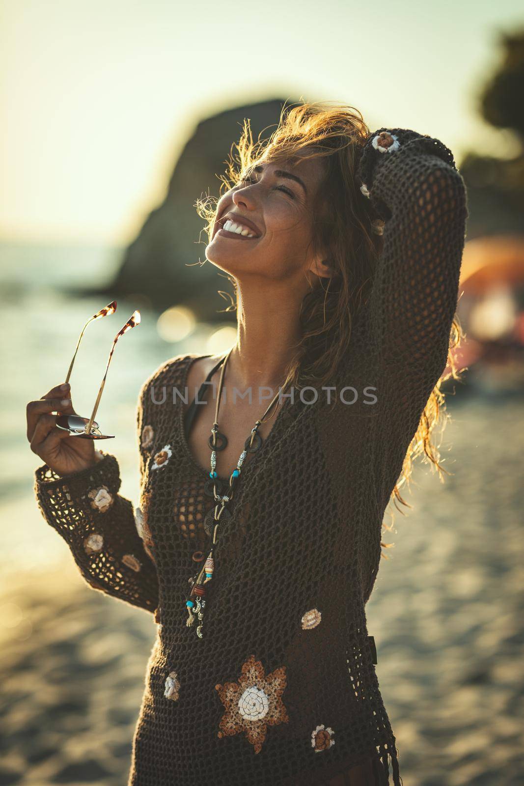 A beautiful young woman is having fun and relaxing on the beach at the sunset. 