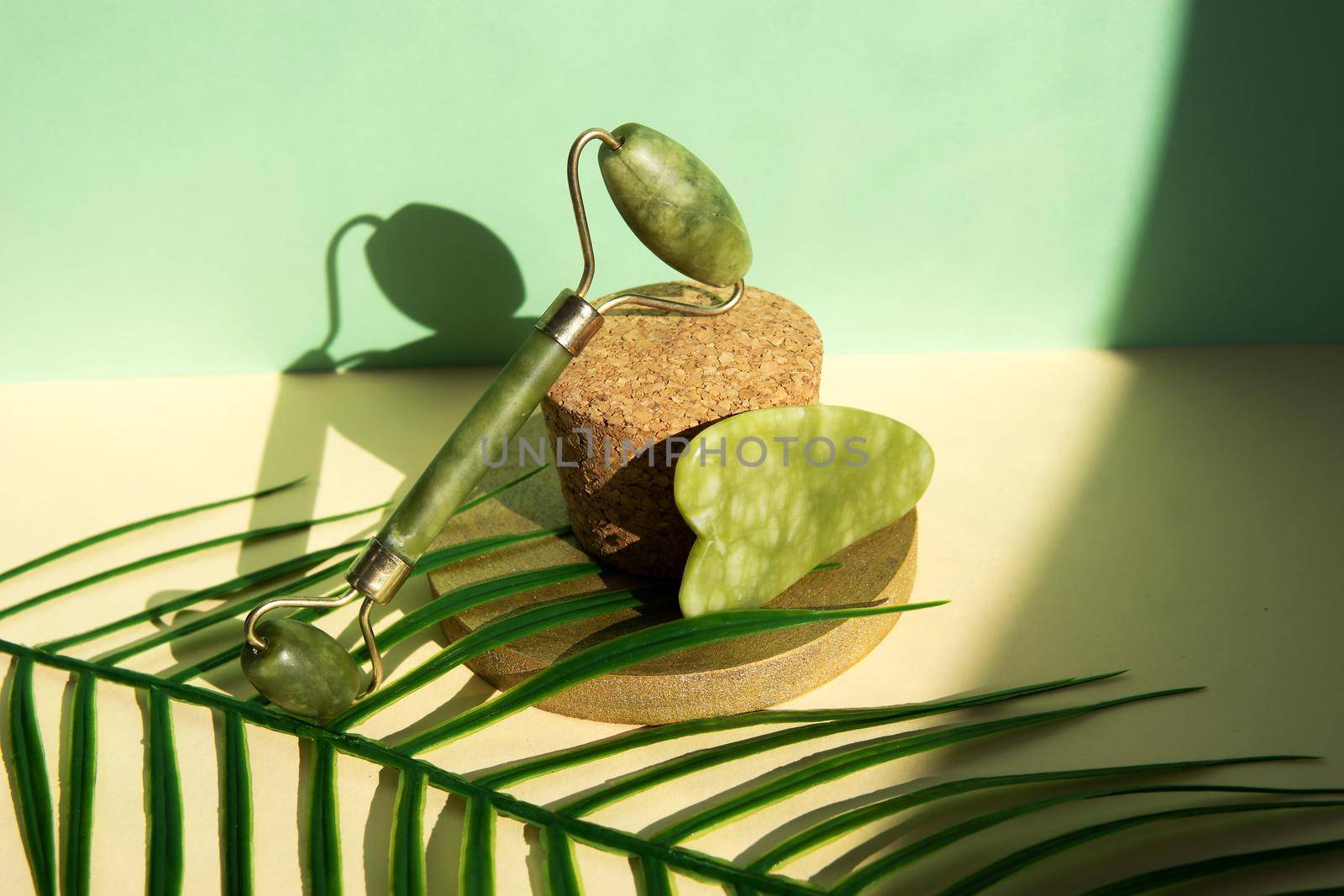 Jade Gua sha scraper and facial massager on beige background. Hard light, shadows, the concept self-care. Facial care. Zero waste. Lifting and toning treatment at home.