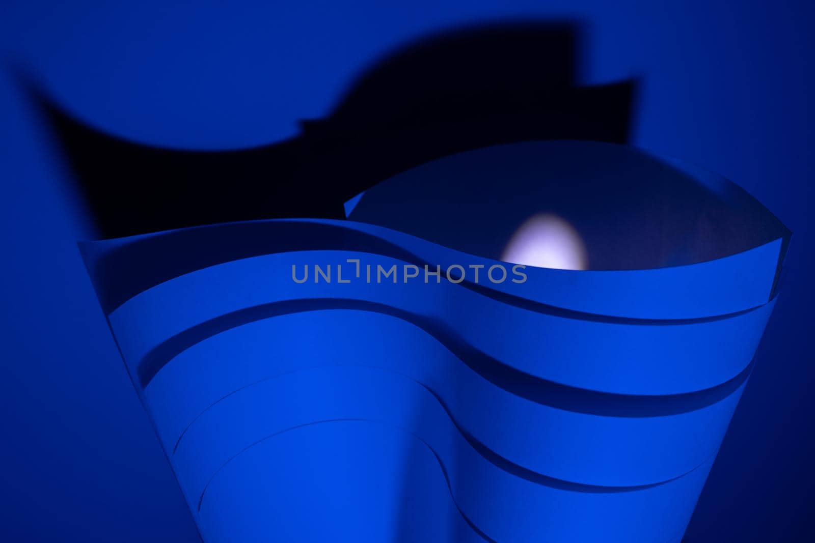 Abstract art. Blue paper waves with backlight and contrasting shadow. Abstract design. Handmade.
