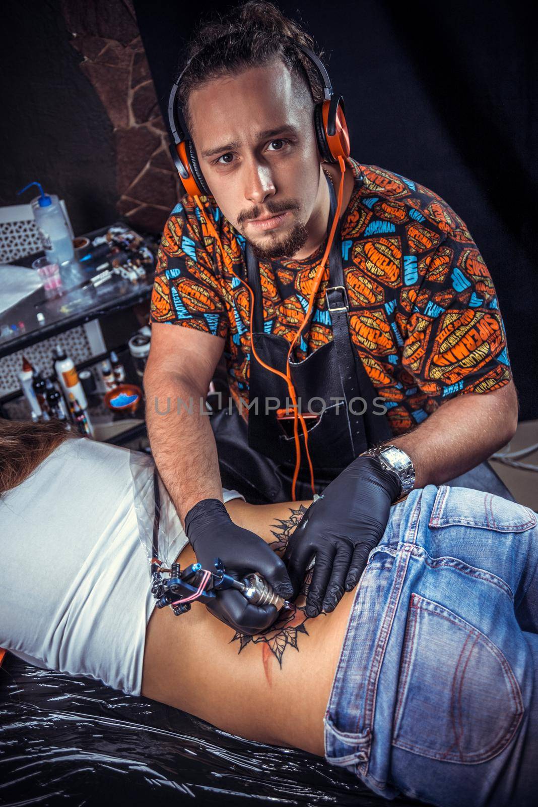 Master tattooist makes a tattoo on the skin in tattoo parlor./Professional tattooist doing tattoo picture in tattoo parlour.