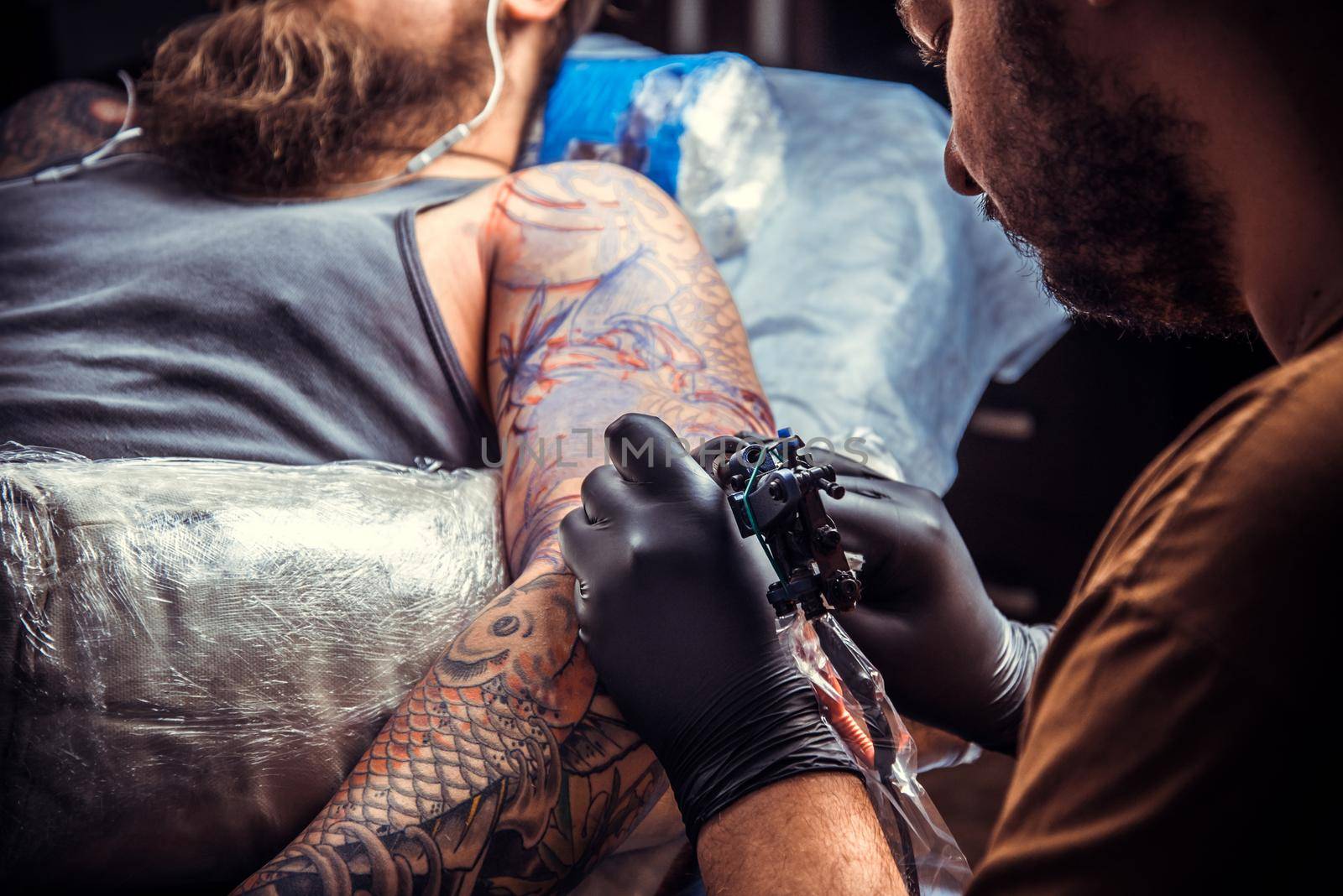 Tattoo artist working tattooing in tattoo parlour./Professional tattoo artist makes cool tattoo in tattoo studio.