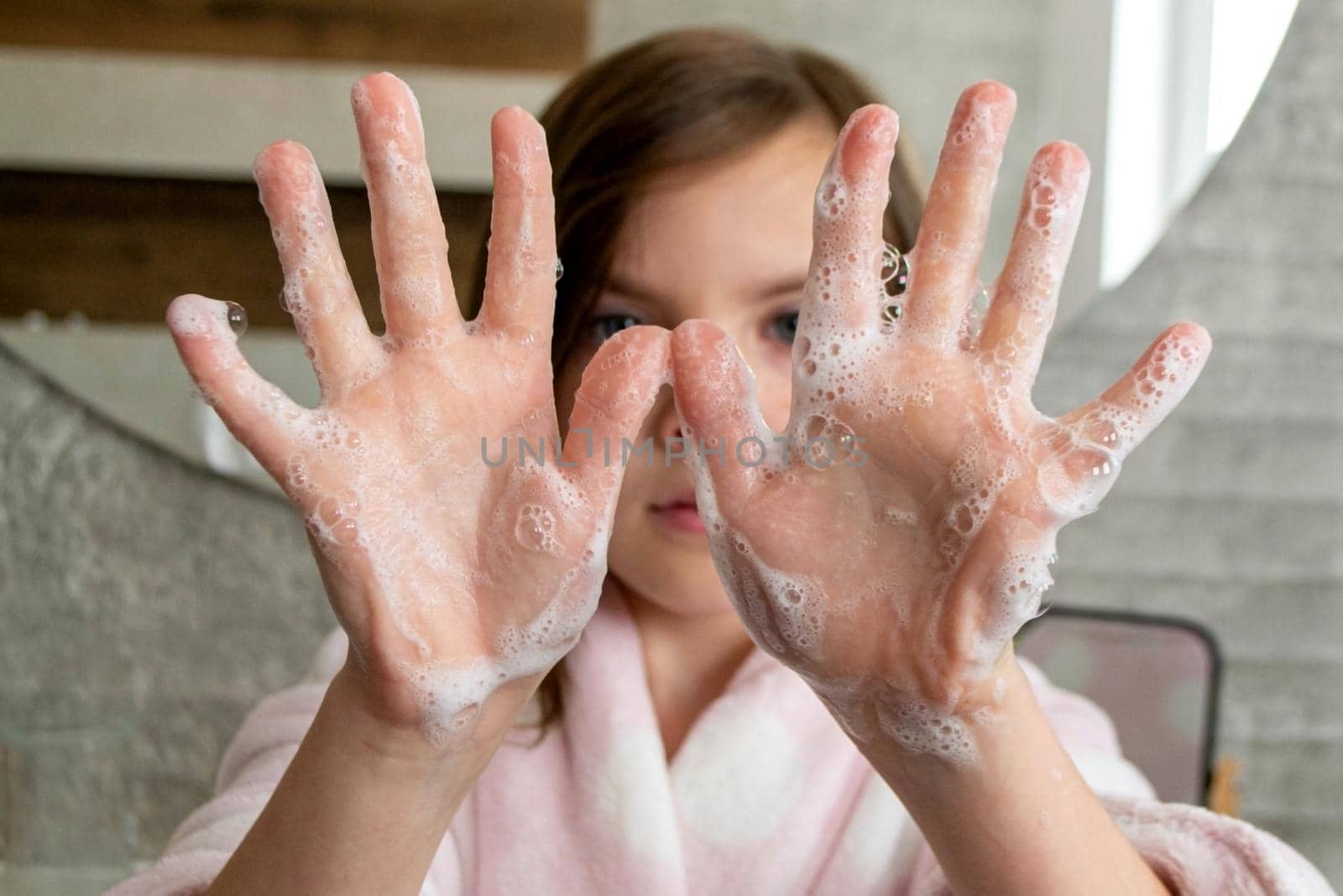 Little girl washing hands with water and soap in bathroom. Happy kid showing soapy palms. Hands hygiene and virus infections prevention. . High quality photo