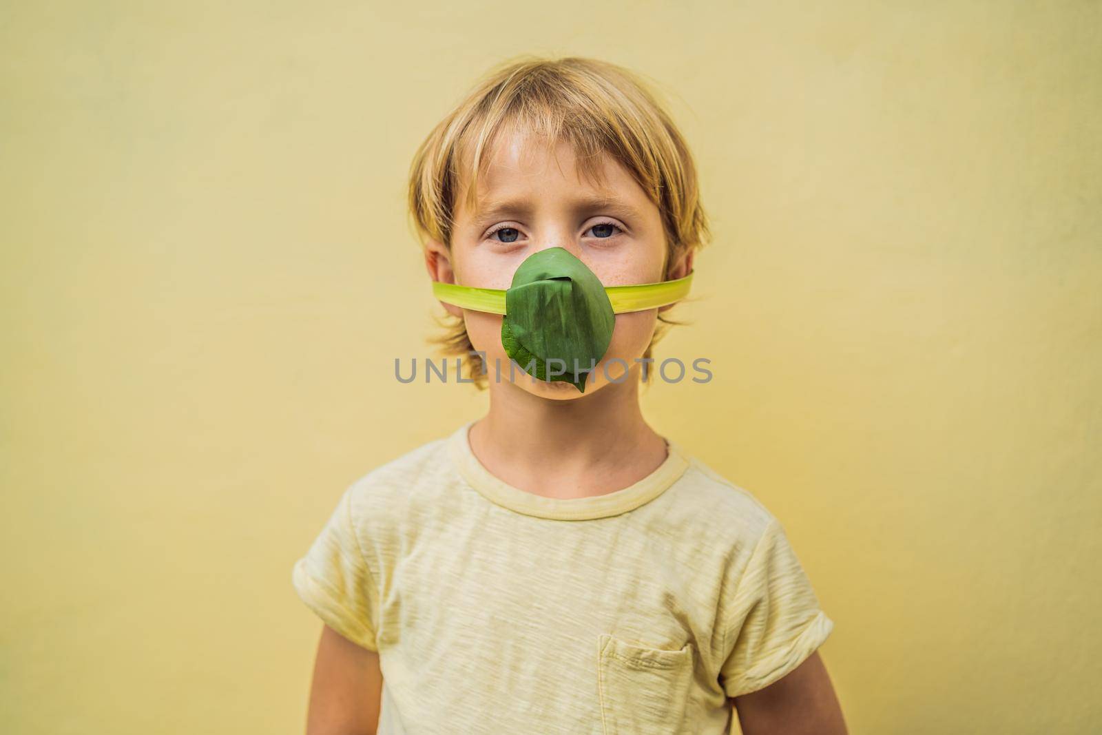 The child made himself a face mask from the leaves to protect himself from air pollution. Air purification for children concept. Trees purify the air concept by galitskaya
