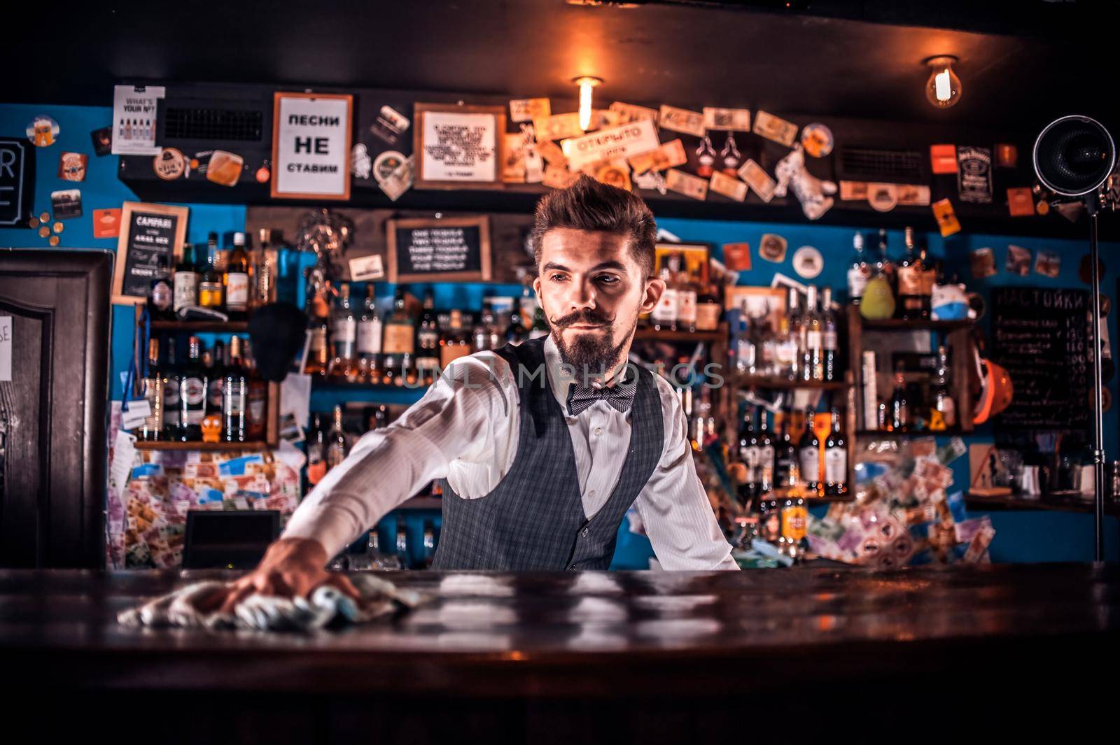 Portrait of bartending adds ingredients to a cocktail while standing near the bar counter in bar by Proff