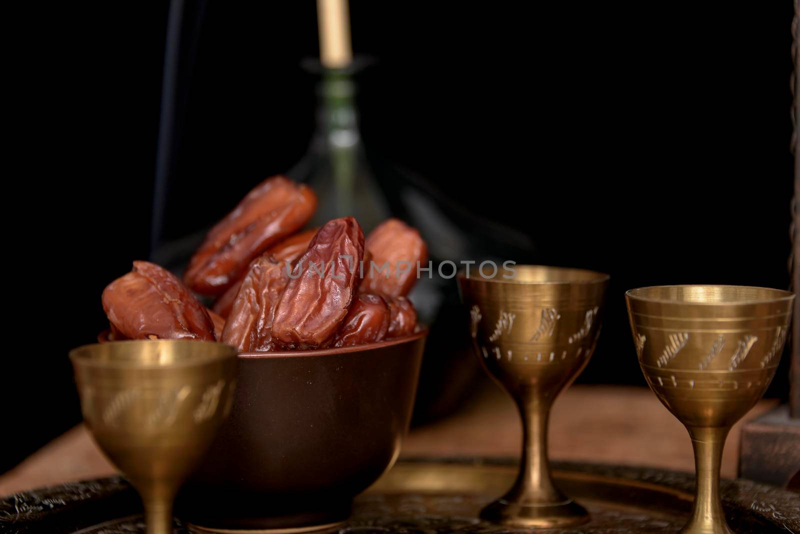 Ramadan concept. Dates closeup in the foreground. Ramadan Lantern on a wooden table. Textured black wall background. by jbruiz78
