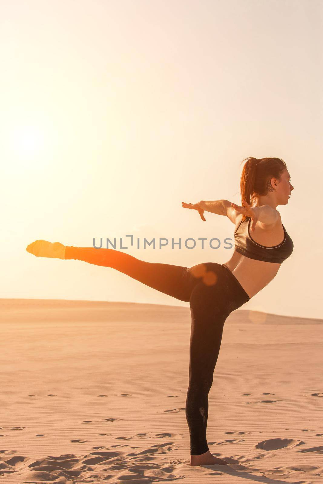 Side view of concentrated fit brunette performing leg and glute workout, doing squats in studio on grey background. Fitness concept