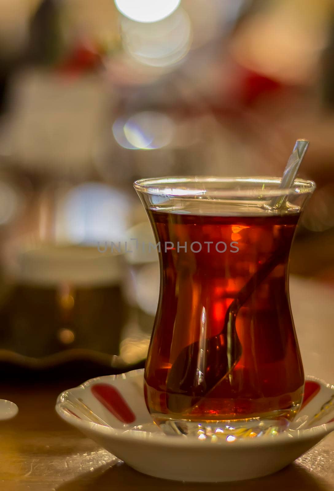 Hot Turkish tea with spoon outdoors on the table. Turkish tea and traditional Turkish culture concept. Vertical. Close up