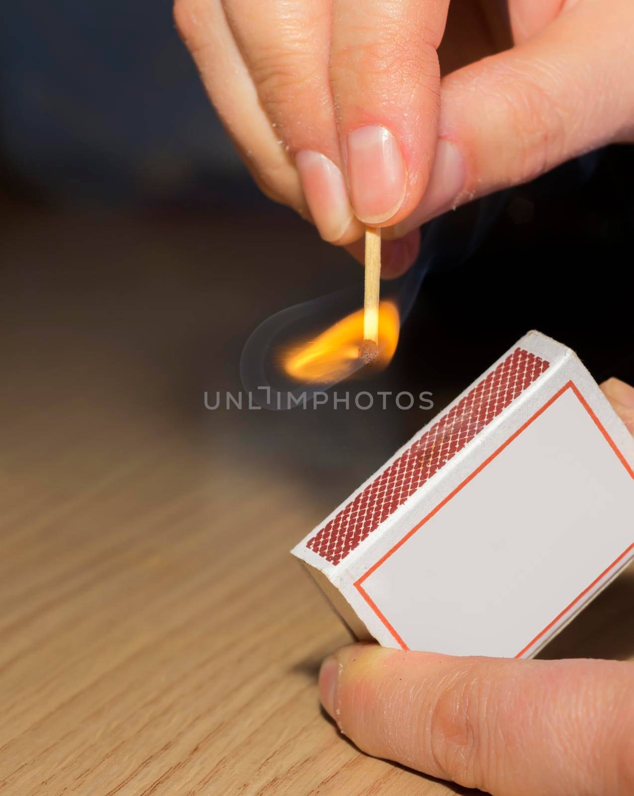 To light a match. The woman lights a match fire from a box of matches by EdVal