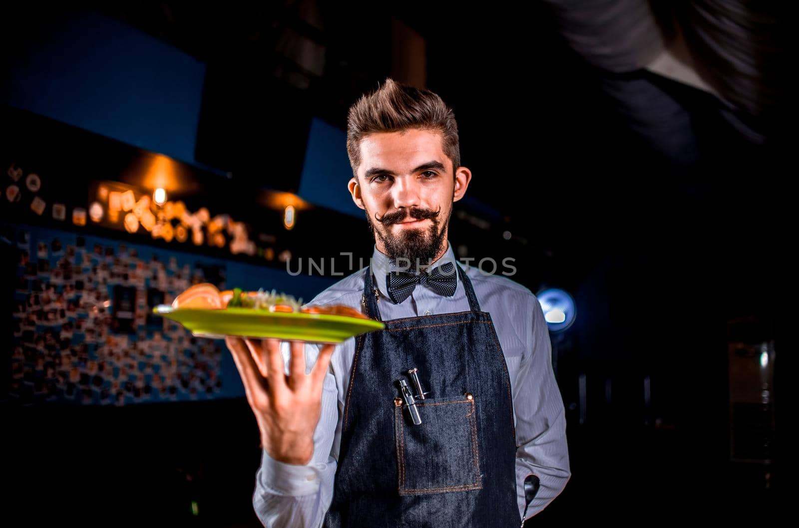 Young restaurant employee carries salad in the restaurant.