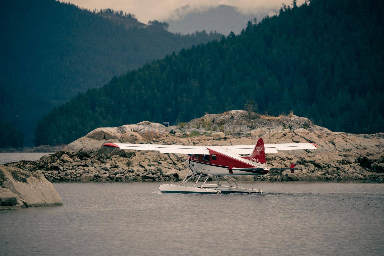 White and red Dehavilland Beaver float plane going through a cut in an an island before take-off. Ballet Bay, British Columbia