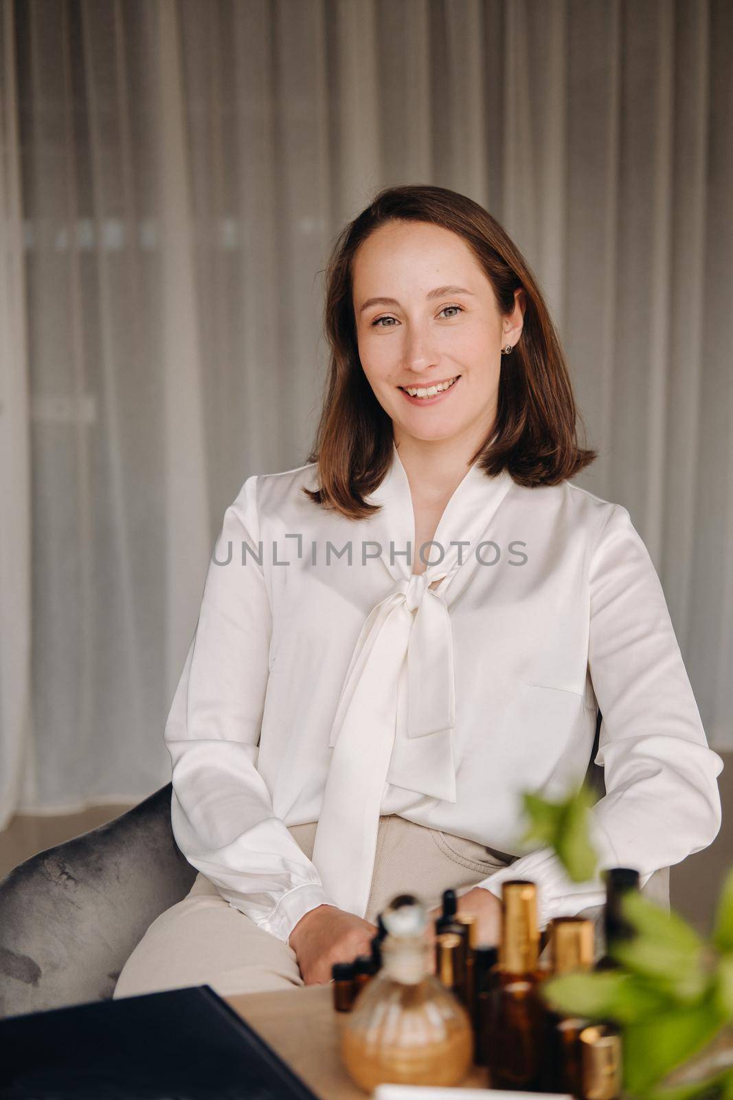 portrait of a smiling girl-woman sitting in an armchair. An aromatherapist in a white blouse is sitting in the office by Lobachad