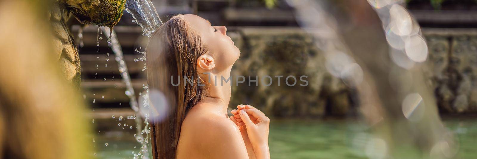 Young woman in hot springs banjar. Thermal water is released from the mouth of statues at a hot springs in Banjar, Bali, Indonesia. BANNER, LONG FORMAT