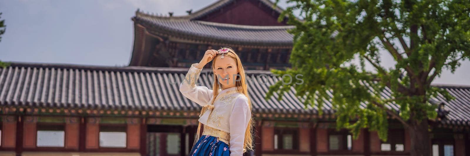 Young caucasian female tourist in hanbok national korean dress. Travel to Korea concept. National Korean clothing. Entertainment for tourists - trying on national Korean clothing BANNER, LONG FORMAT by galitskaya