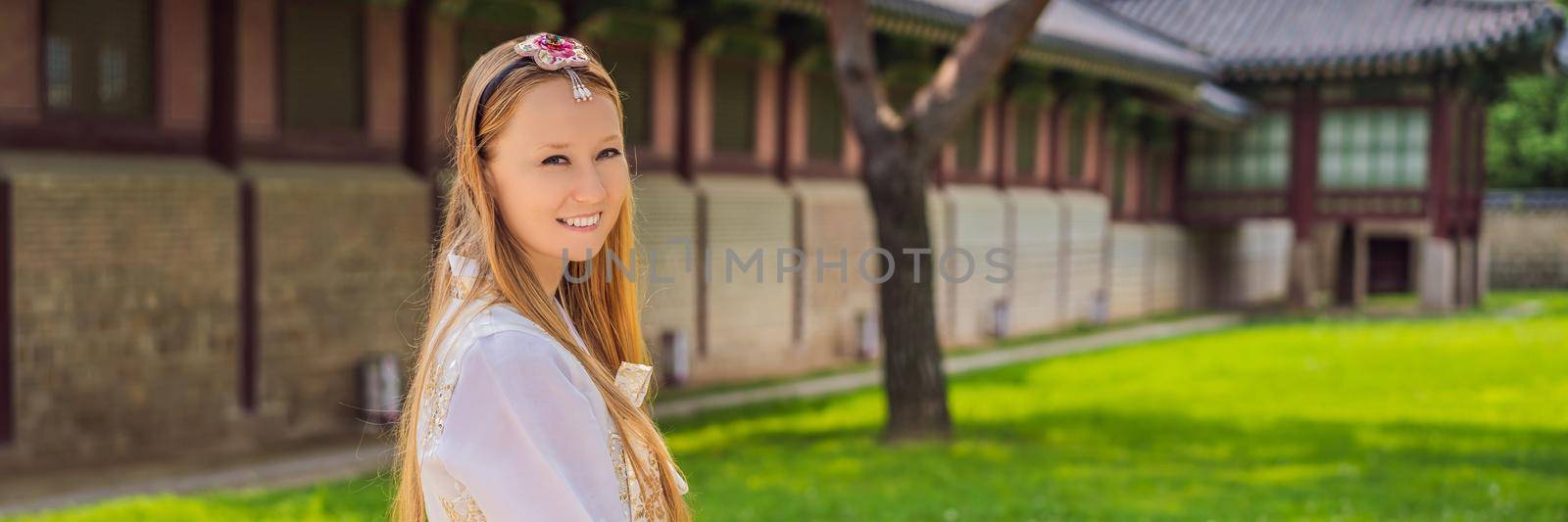 Young caucasian female tourist in hanbok national korean dress. Travel to Korea concept. National Korean clothing. Entertainment for tourists - trying on national Korean clothing. BANNER, LONG FORMAT