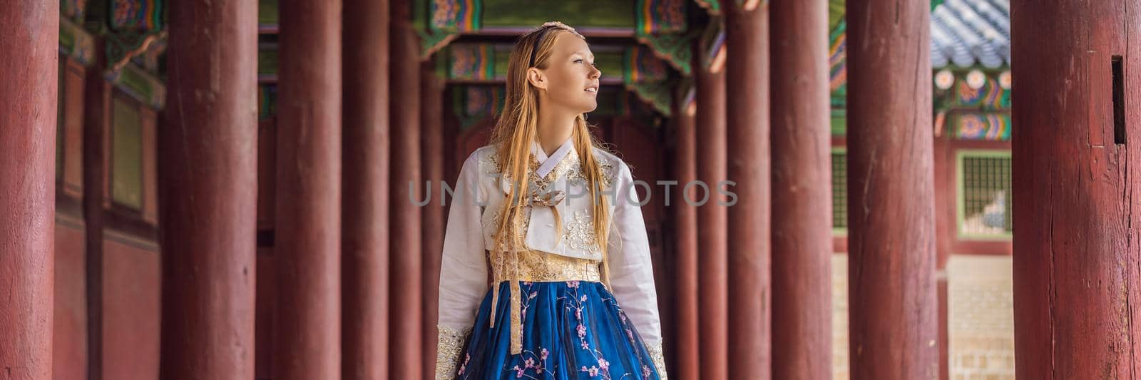 Young caucasian female tourist in hanbok national korean dress Travel to Korea concept. National Korean clothing. Entertainment for tourists - trying on national Korean clothing BANNER, LONG FORMAT by galitskaya