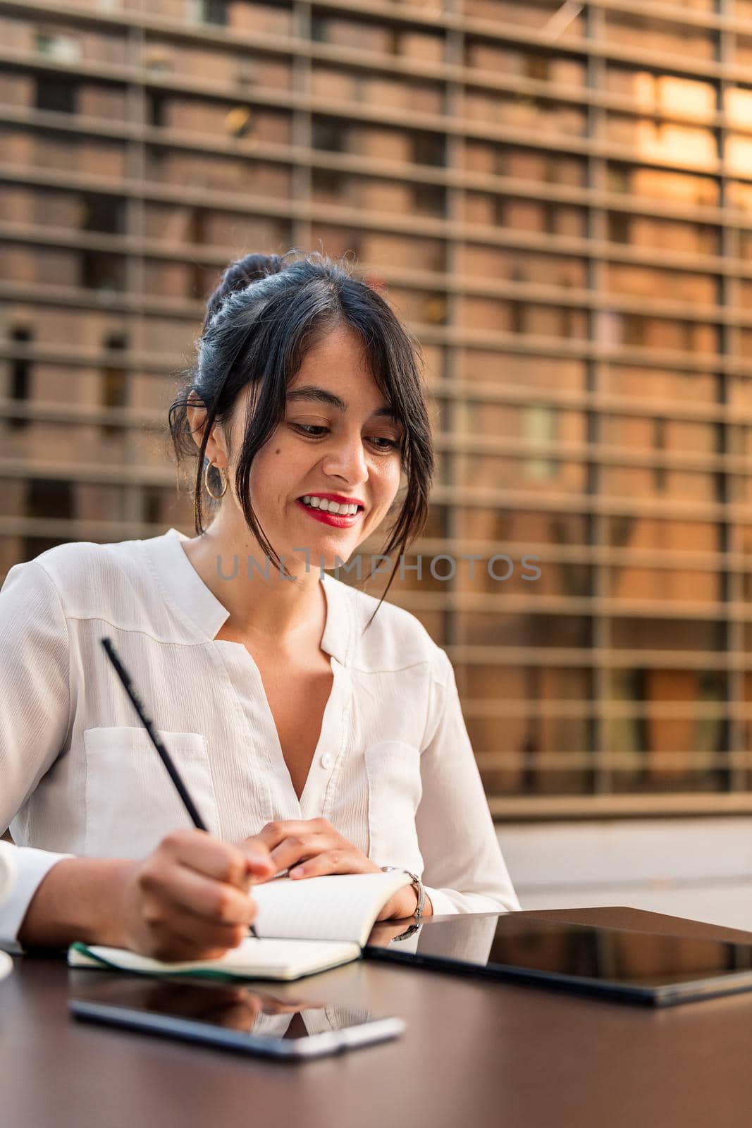 businesswoman working and taking notes on the terrace of a coffee shop, concept of digital entrepreneur and urban lifestyle, copy space for text