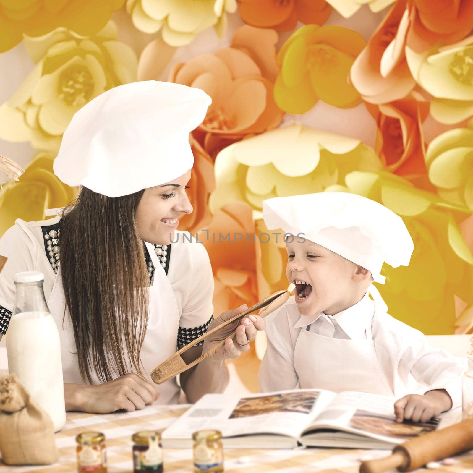 A happy mother and her child in the form of cooks prepare a delicious lunch by SmartPhotoLab