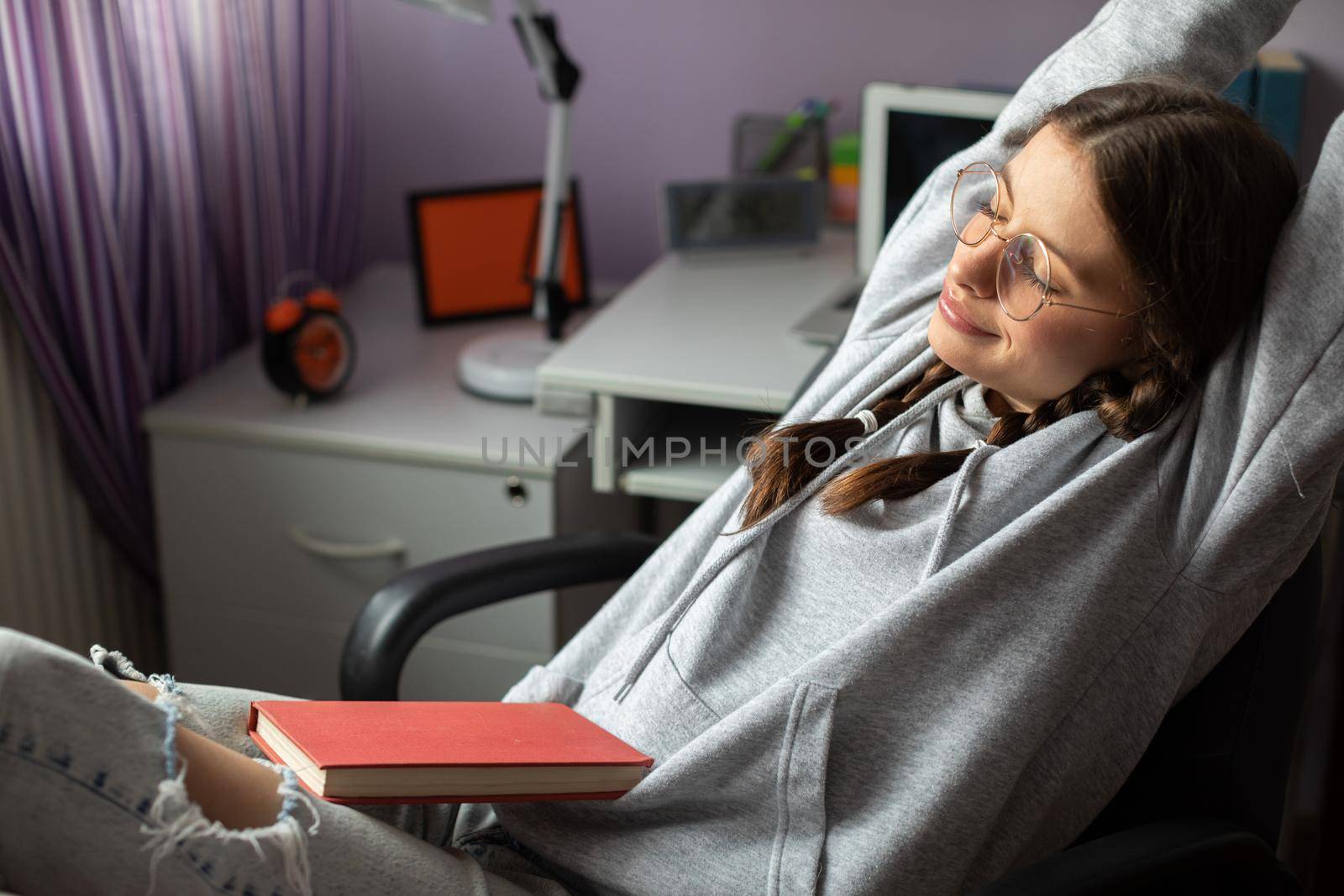 Dragging. Young girl with glasses and two braids. Brunette girl while pausing to read a book. A room in a house.