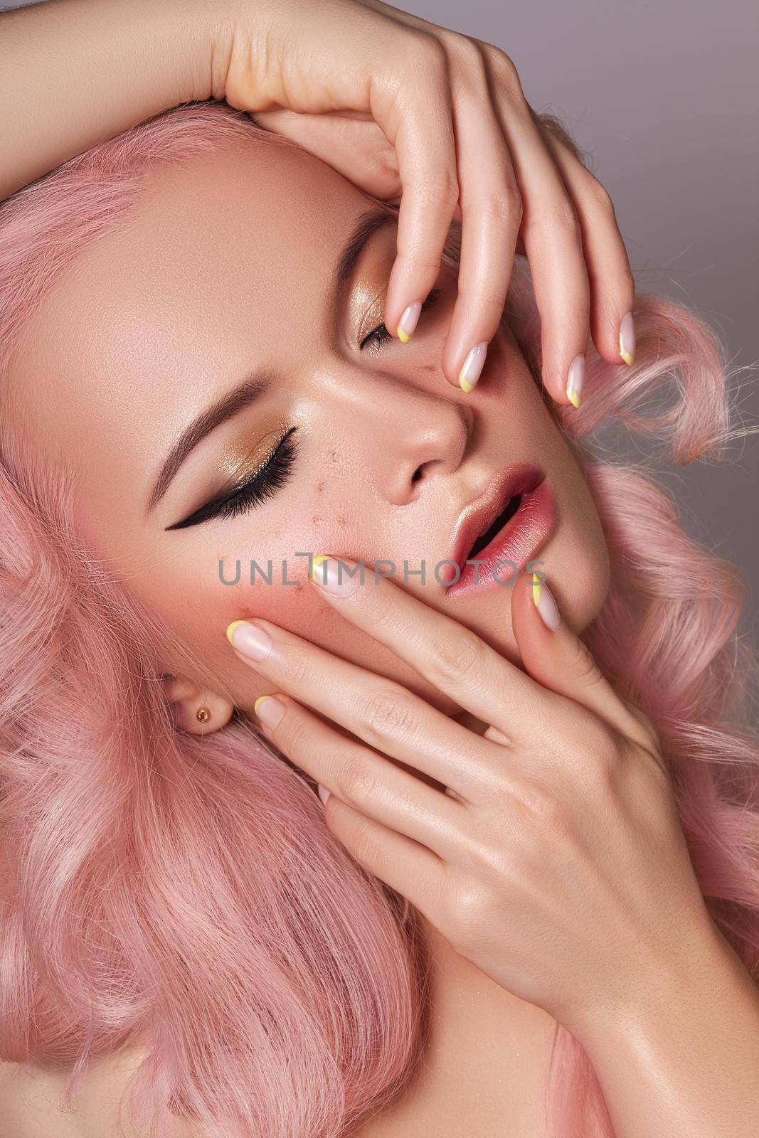 Beautiful Woman with Curly Colored Hairstyle and Fashion Make-up. Beauty Soft-Girl Style with Tender Pink Hair, Yellow French Manicure, Spring Makeup. Valentines Day, March 8 or Womens Day Look