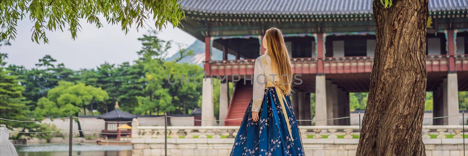 Young caucasian female tourist in hanbok national korean dress Travel to Korea concept. National Korean clothing. Entertainment for tourists - trying on national Korean clothing BANNER, LONG FORMAT by galitskaya