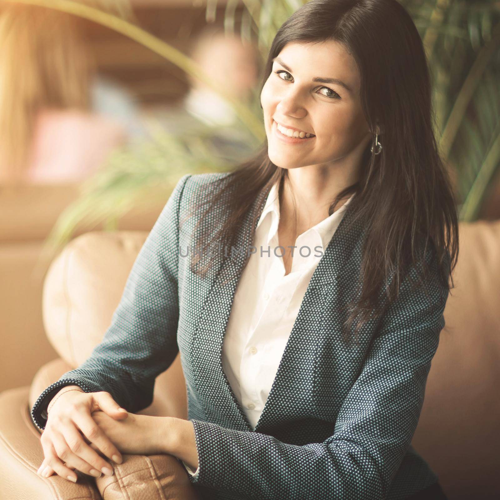 Beautiful business woman. Resting on the couch after a deal smiling and posing to the camera