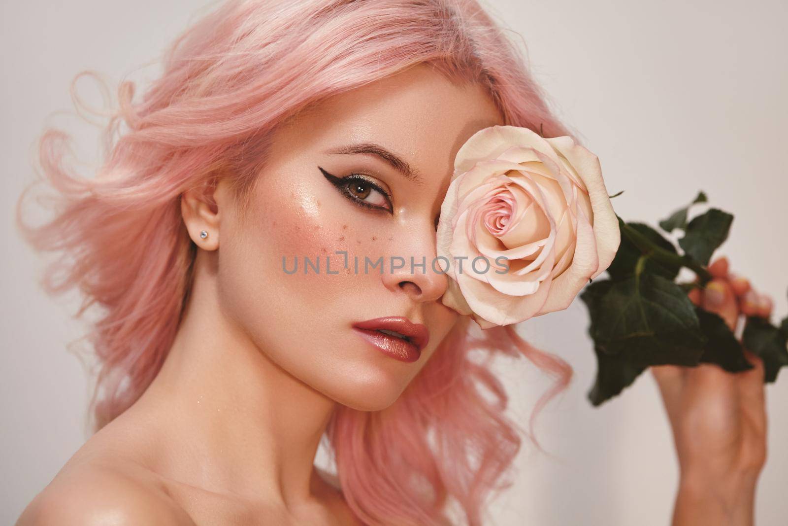 Soft-Girl Style with Trend Pink Flying Hair, Fashion Make-up. Woman Face with Fake Freckles and Rose Flowers. Blonde Female Model with perfect Fresh Clean Skin, Blush Rouge