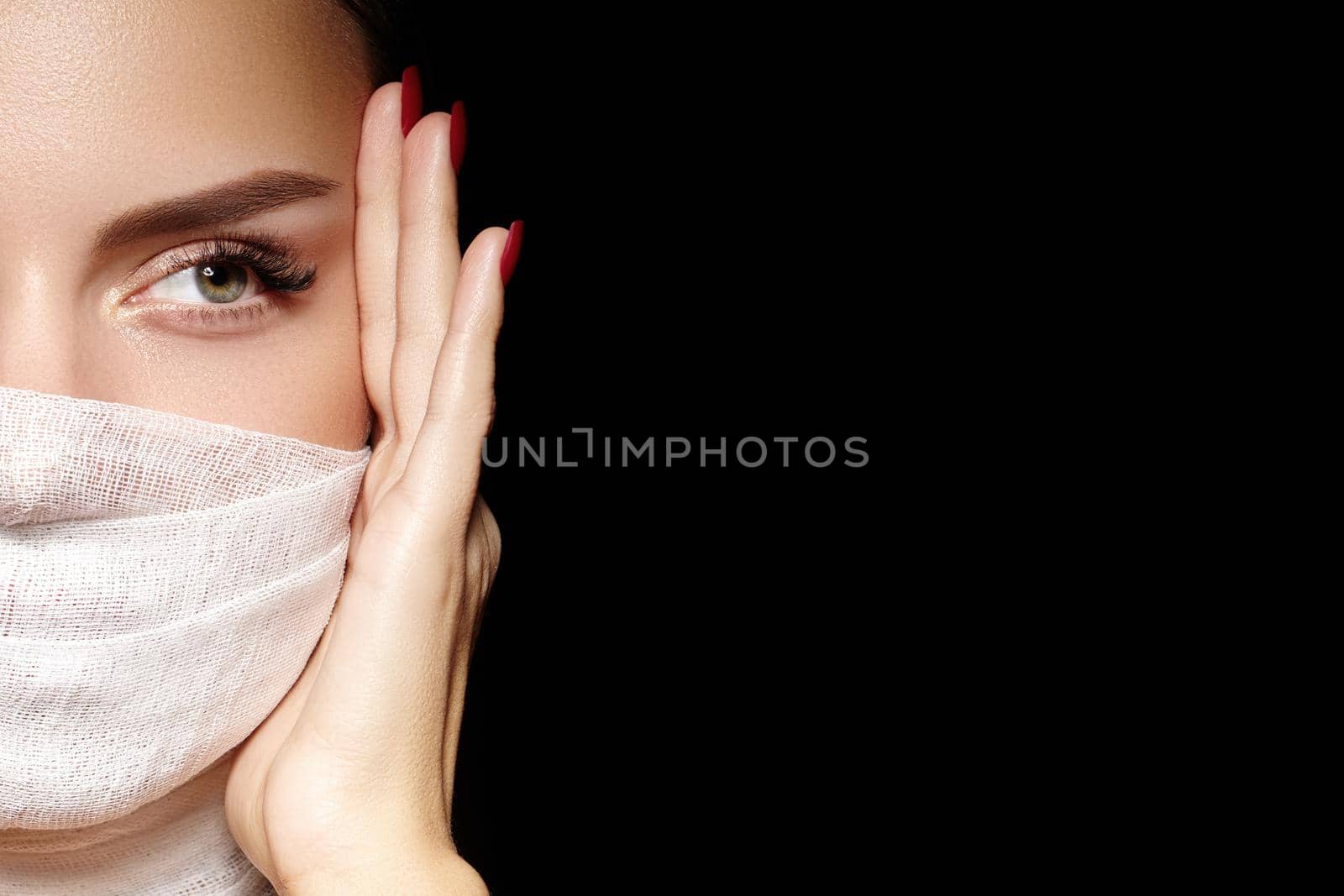 Beautiful woman with a bandage mask on face. Fashion eye make-up. Beauty plastic surgery or protection hygiene in viral covid-19 pandemic