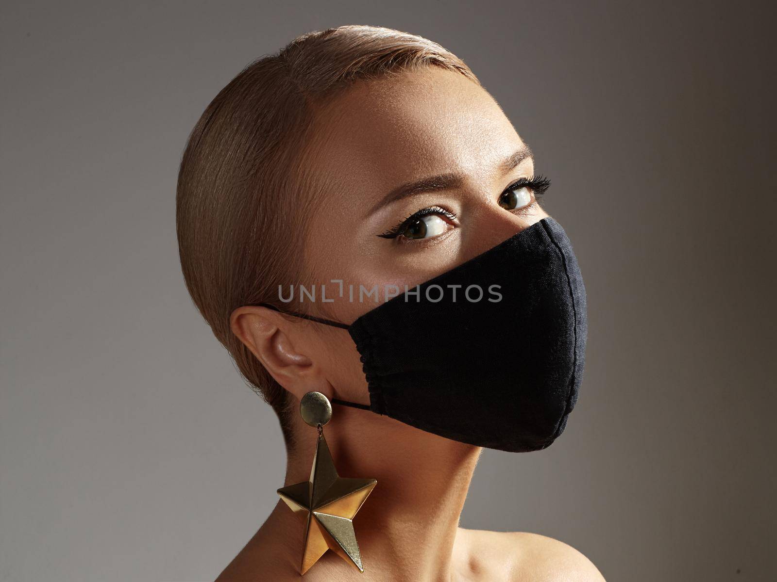 Beautiful Woman with Black Mask on Face. Fashion Eye Make-up and Gold Accessories. Beauty Plastic Surgery or Protection Hygiene in Viral Covid-19 Pandemic