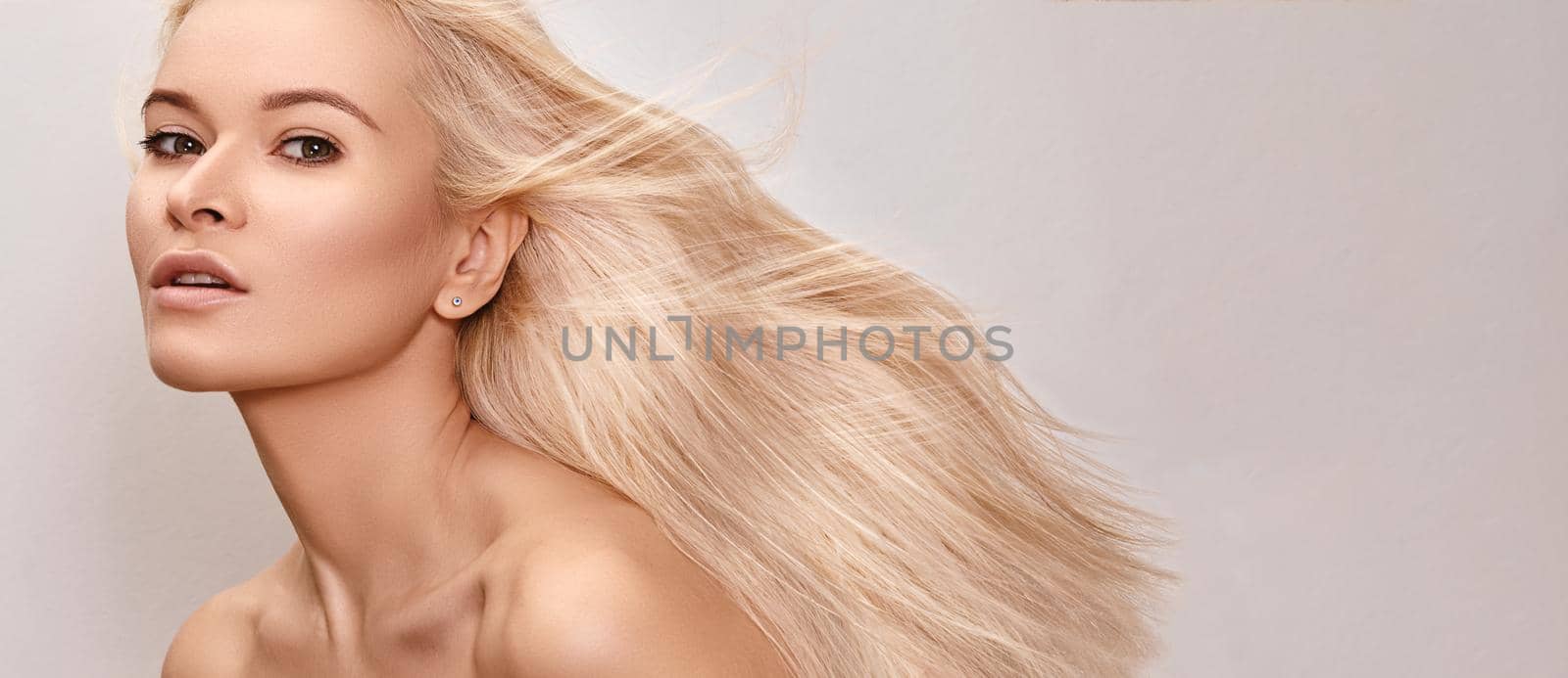 Beautiful woman with magnificent blond hair. Happy model face with windswept flying hair. Shiny long health hairstyle. Beauty and haircare