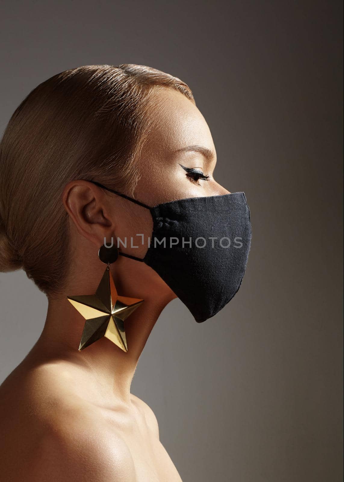 Beautiful Woman with Black Medical Mask on Face. Fashion Eye Liner Make-up. Festive Look with Gold Accessory. Protection Hygiene in Viral Covid-19 Pandemic