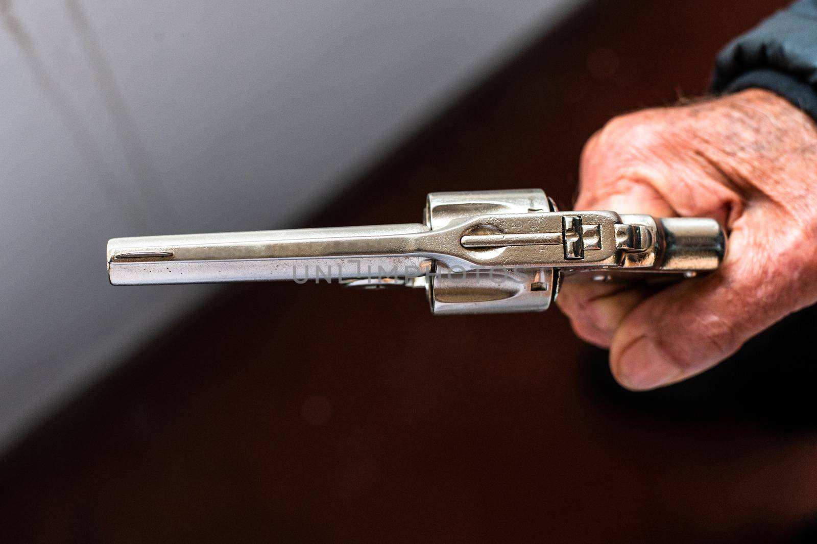 An old hand holding an antique revolver in a shooting position. by Peruphotoart