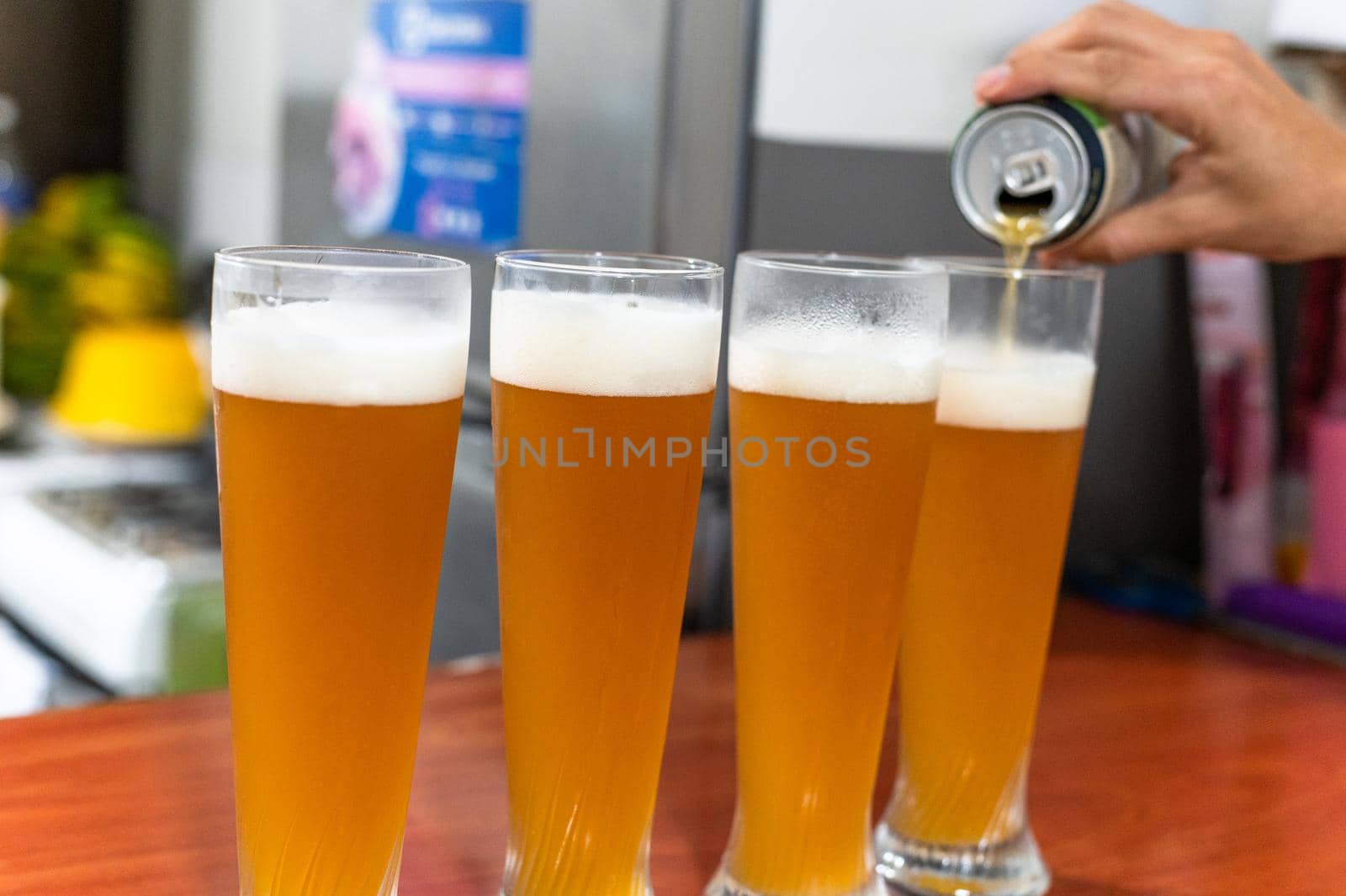 hand pours beer from a can into a glass. by Peruphotoart