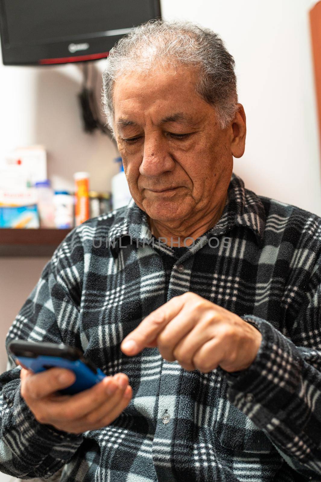 Happy senior Caucasian man looking at cellphone screen browse wireless internet. Smiling modern mature 70s grandfather text or message on smartphone. Elderly use cell technologies at home