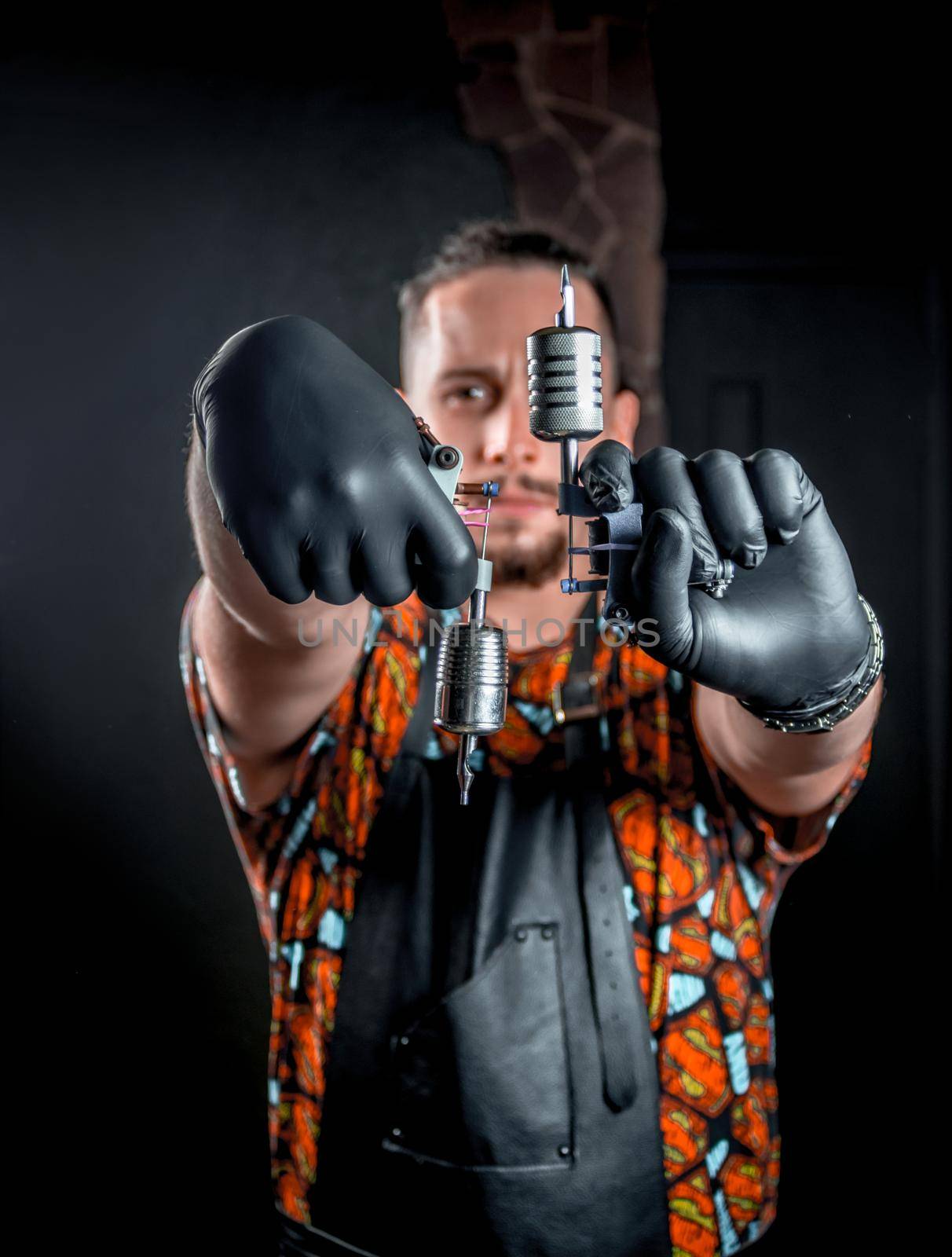 Professional tattooer with a tattoo gun in a tattoo studio by Proff