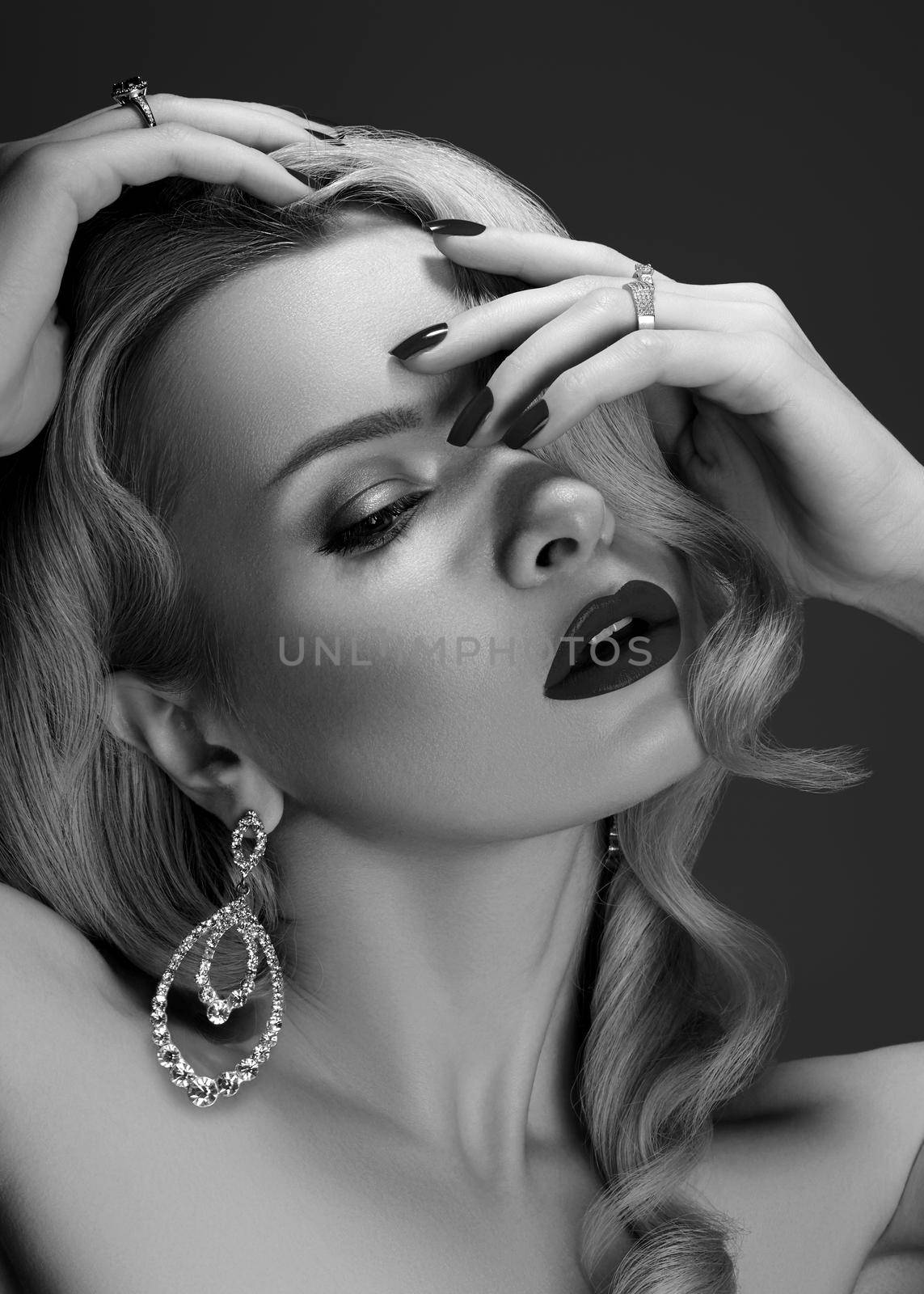 Beautiful Sexy Woman with Fashion Make-up and Blond Curly Wave Hairstyle, Bright Accessories. Glamour Pin-up Girl. American Cinema Diva Style with Brilliant Earrings and Rings in black and white style