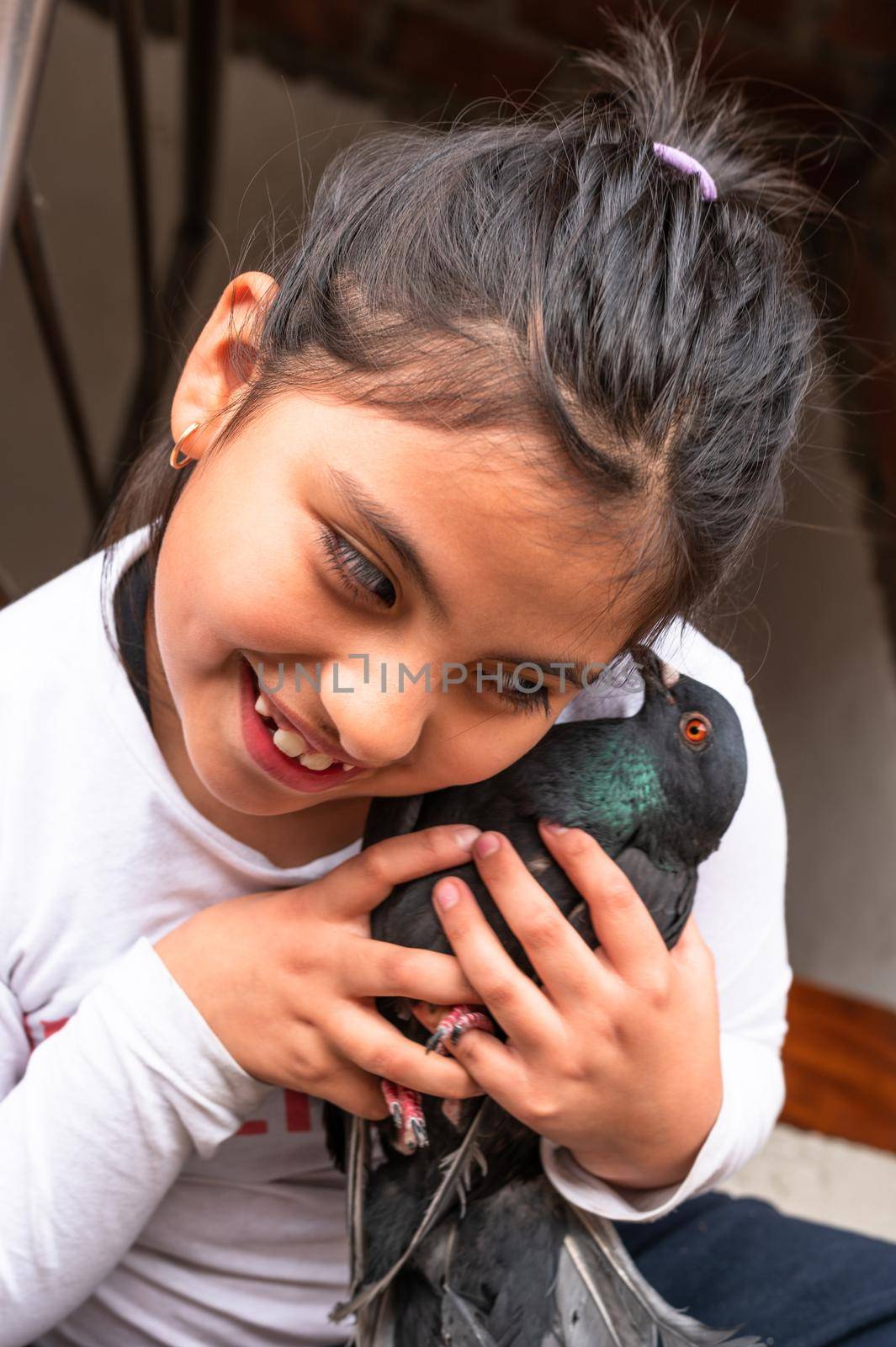 Little smiling girl hugging her pet which is a little pigeon. by Peruphotoart
