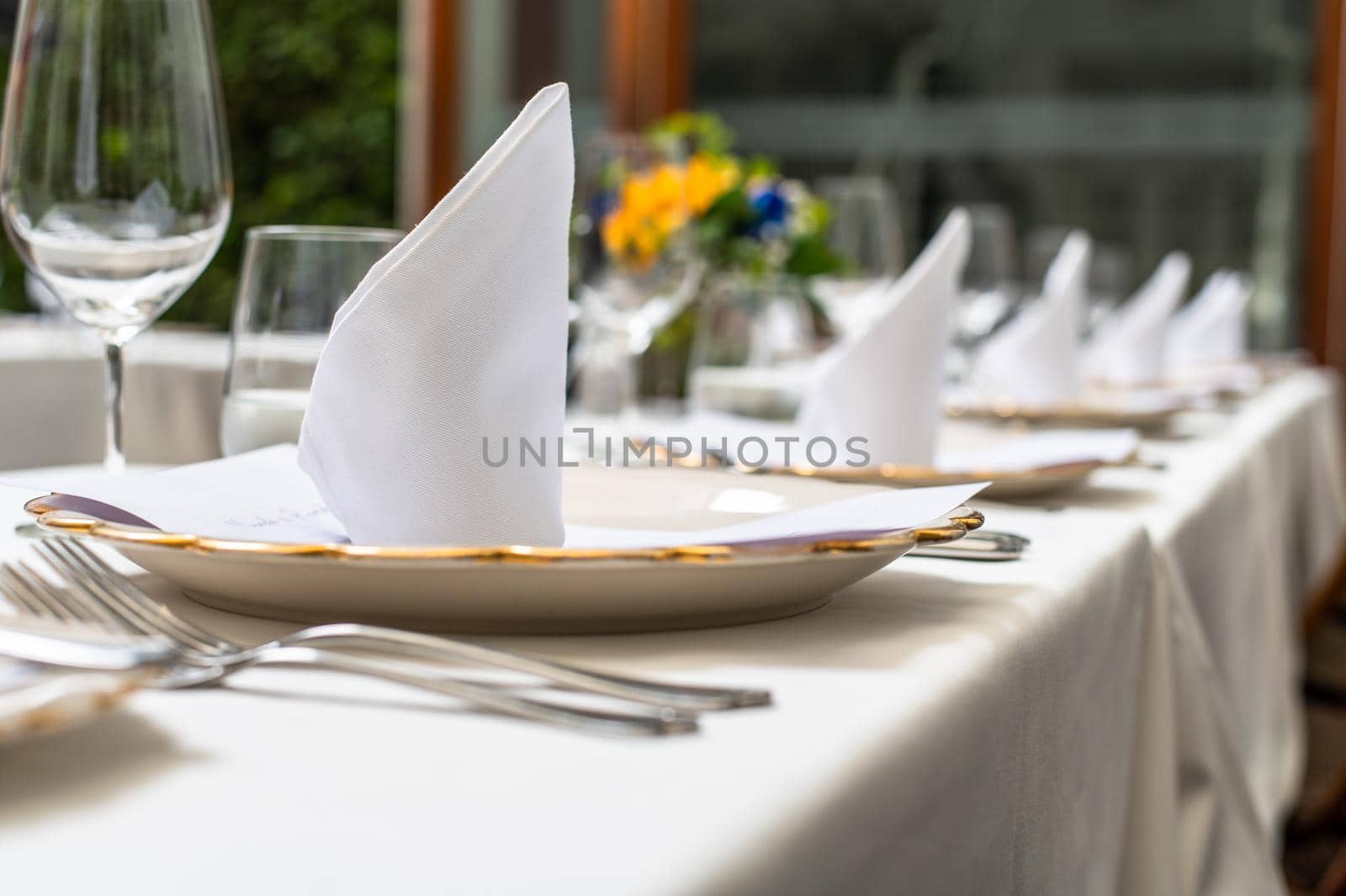 Elegant wedding lunch table decorated with crystal goblets and yellow flowers. by Peruphotoart