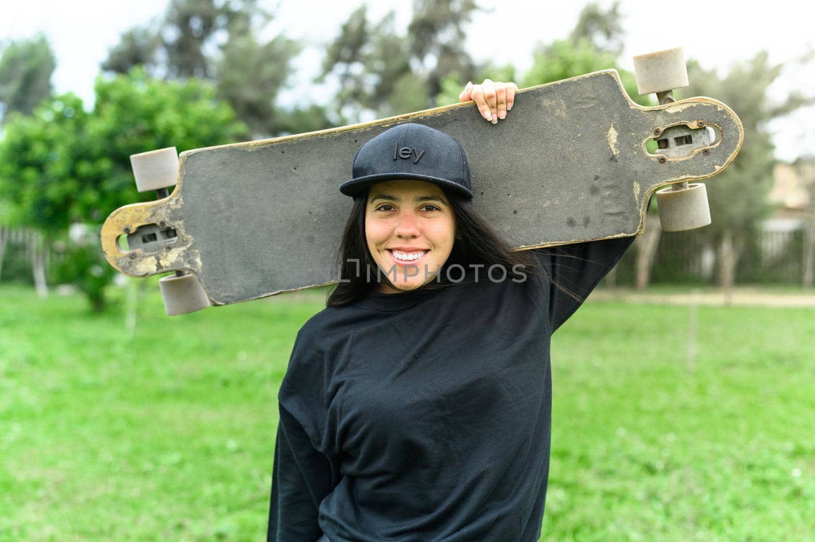 Young girl on longboard smiling. Outdoors, lifestyle. by Peruphotoart