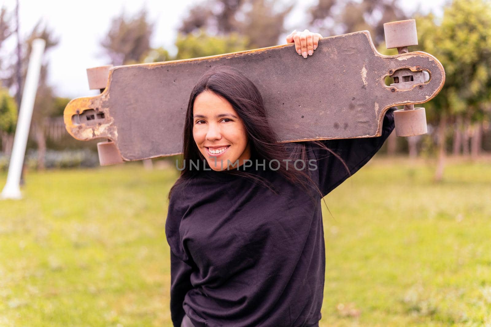 Young girl on longboard smiling. Outdoors, lifestyle. by Peruphotoart