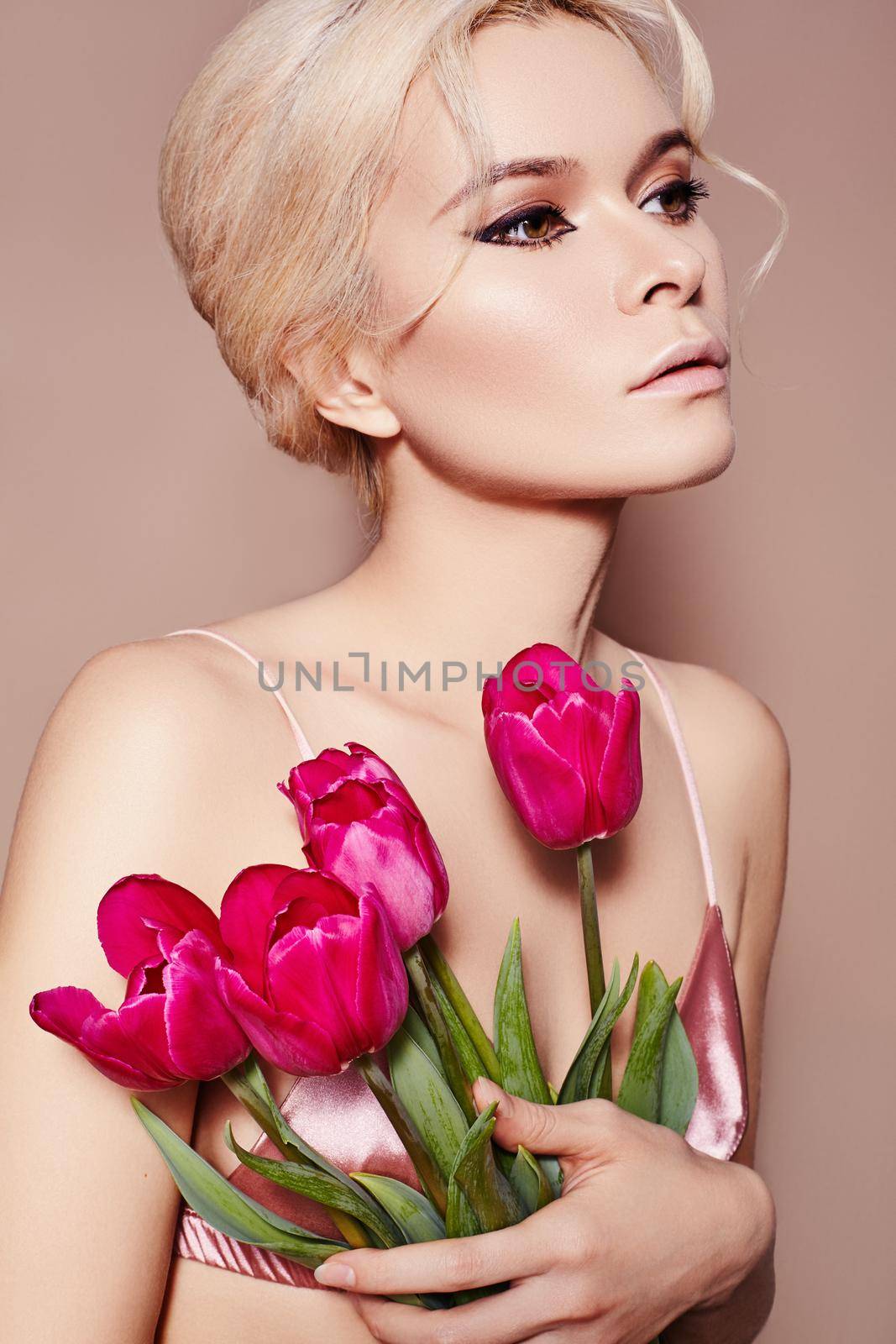 Beautiful sexy Blonde Woman with luxury retro Make-up. Girl with Spring Flowers Bouquet on Beige Background for any Celebrating. Fresh Style for Womans Day or Valentines