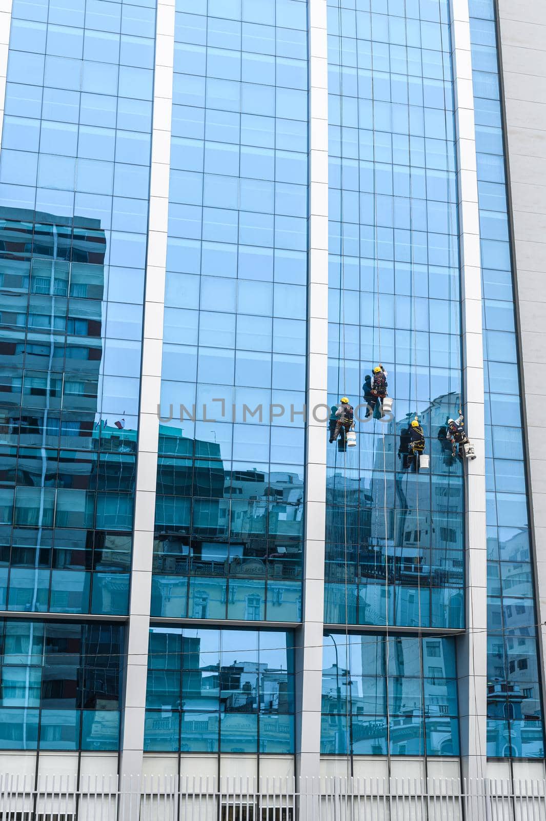 group of workers cleaning windows service on high rise building. by Peruphotoart