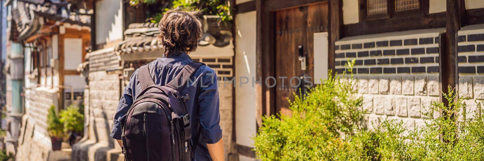 Young man tourist in Bukchon Hanok Village is one of the famous place for Korean traditional houses have been preserved. Travel to Korea Concept BANNER, LONG FORMAT by galitskaya