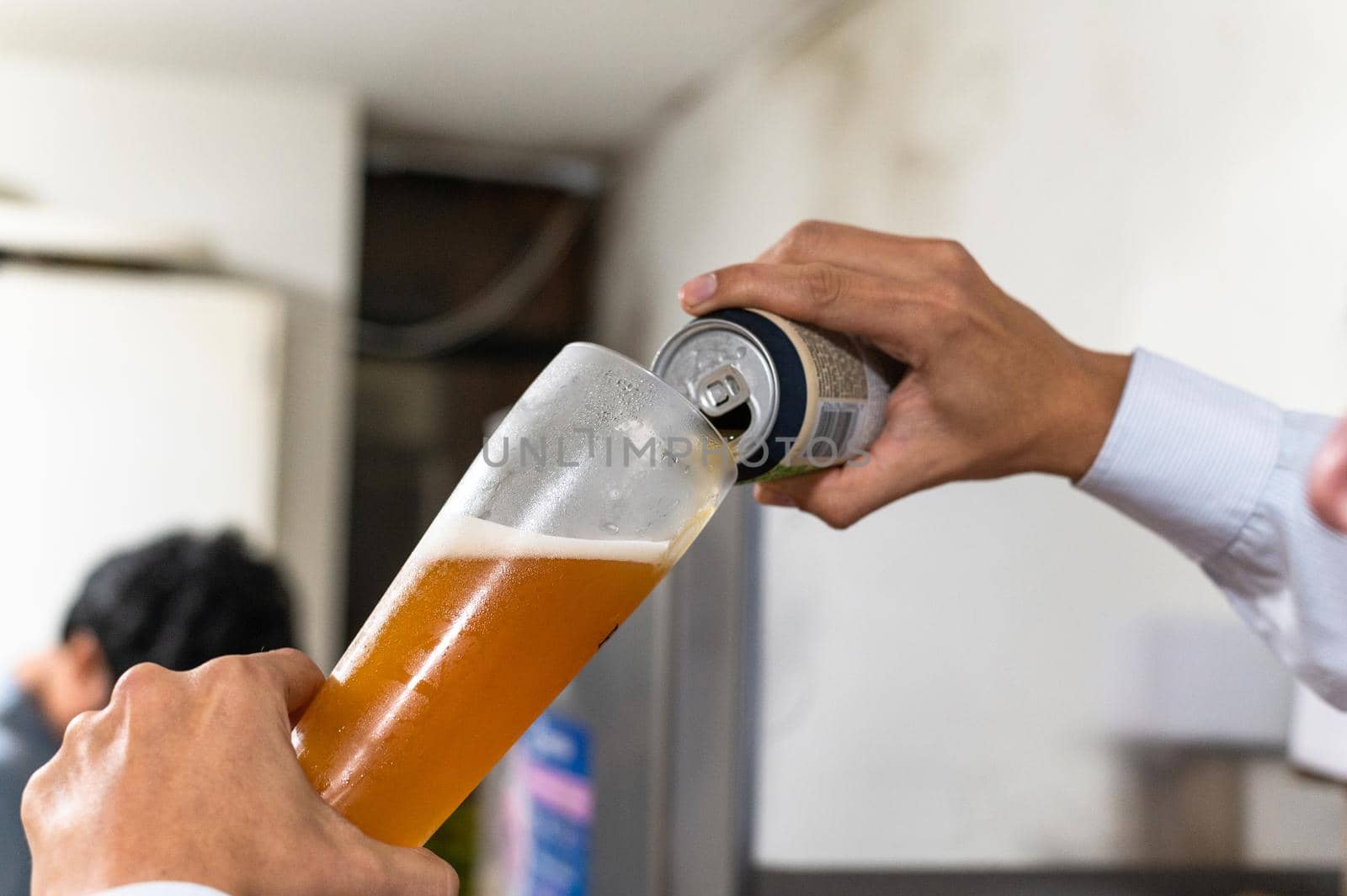 hand pours beer from a can into a glass