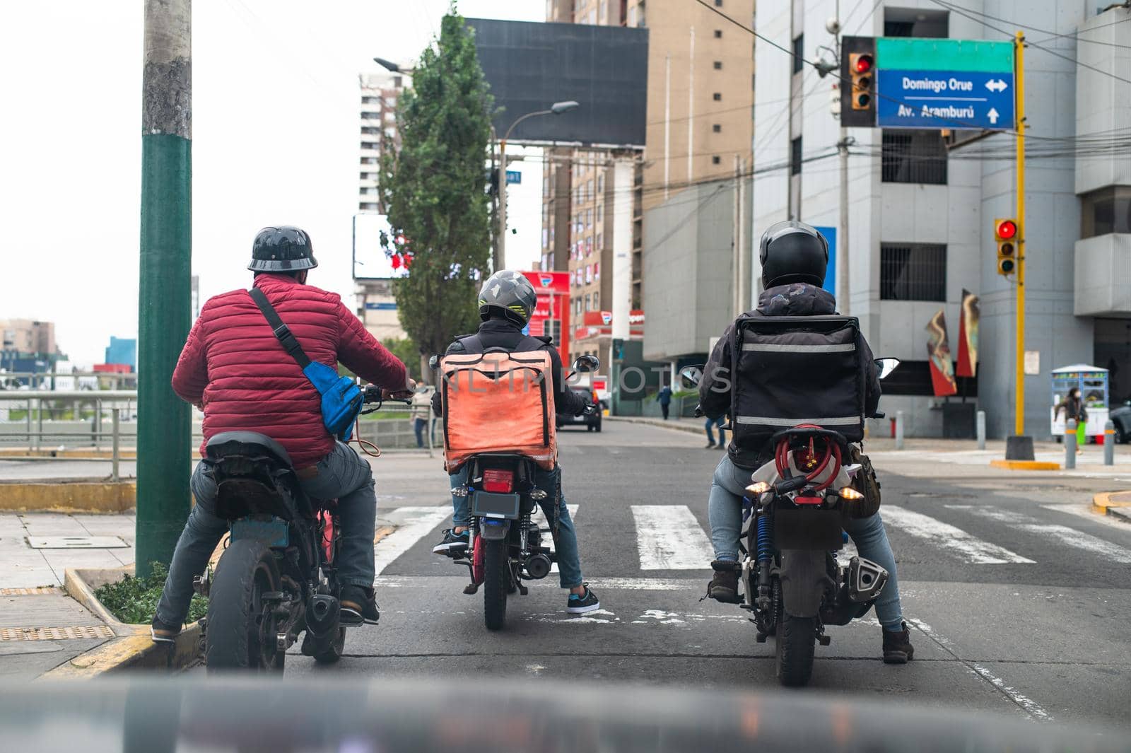 Food delivery driver with backpack on a motorcycle riding along a street. by Peruphotoart