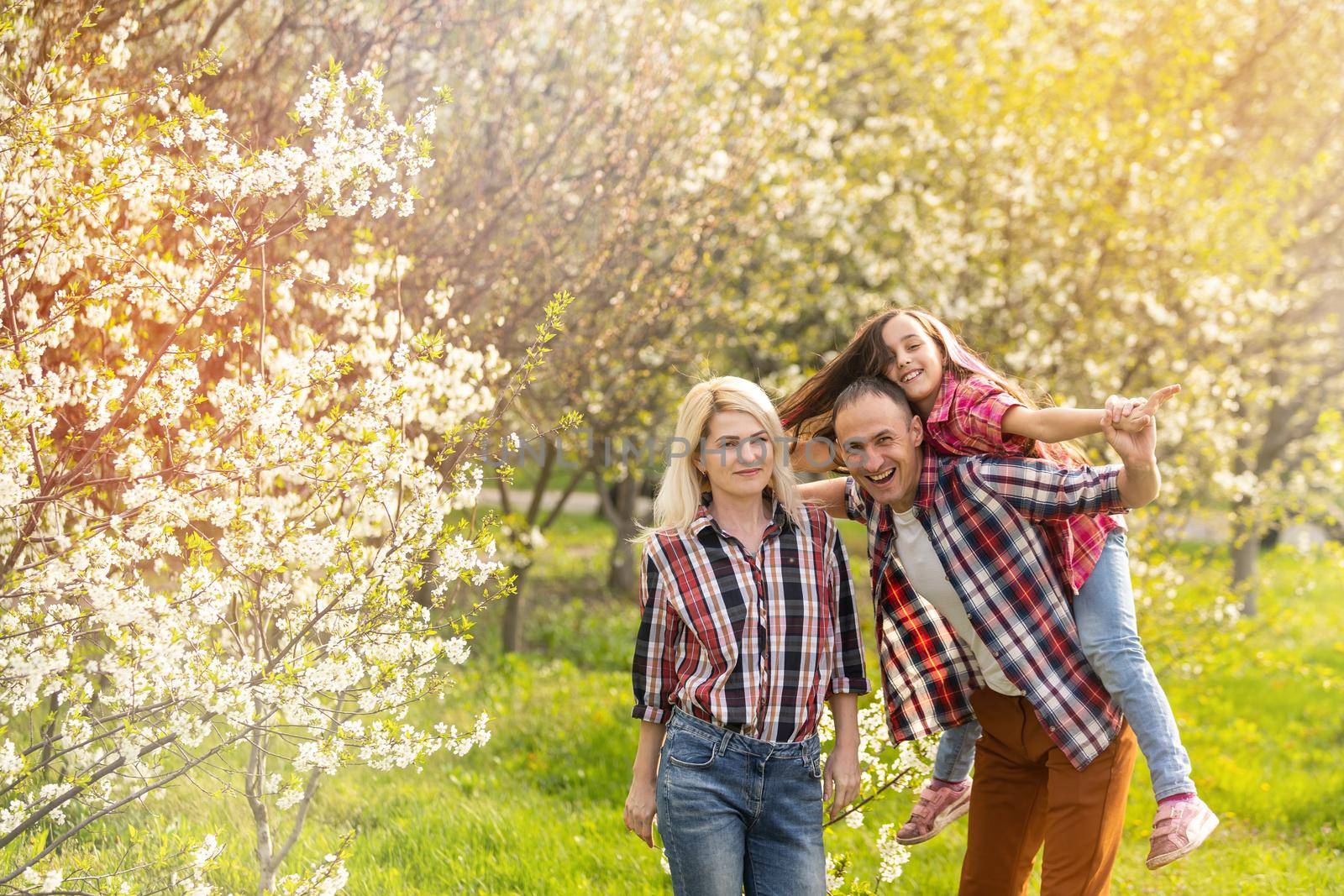 Happy family spending good time together in spring in a flowering garden.